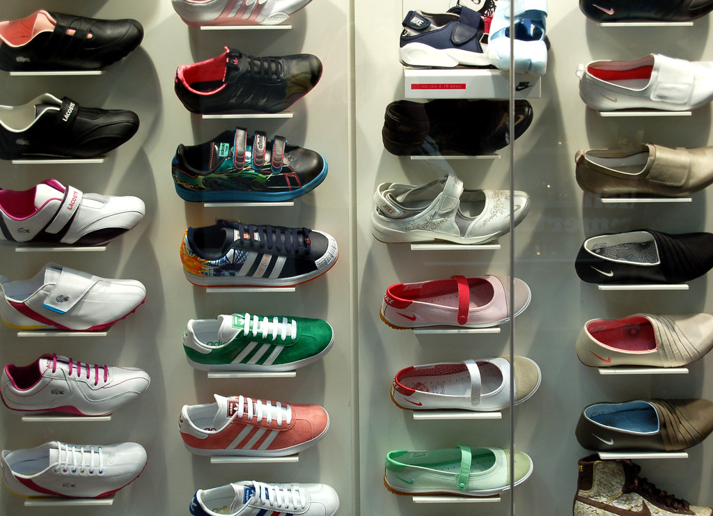 Rows of shoes displayed on wall shelves behind glass