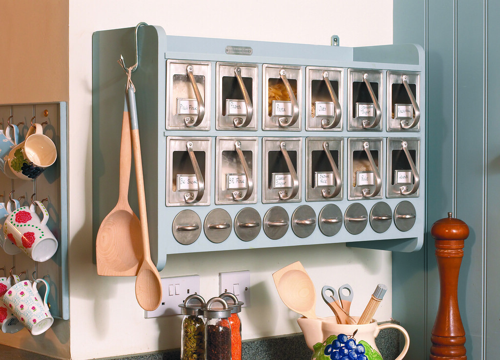 Wall-mounted kitchen spice cabinet with small labeled drawers and utensils nearby