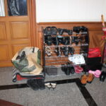 Shoe rack with many shoes beside umbrellas near a wooden entry door