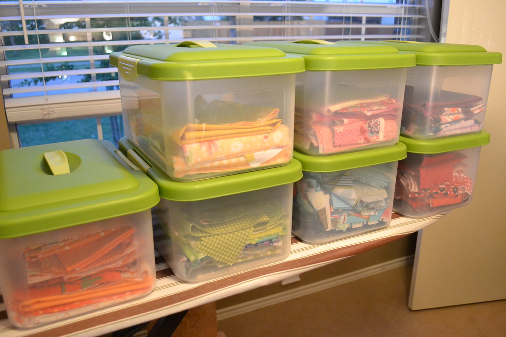 Clear plastic storage bins with green lids on a shelf