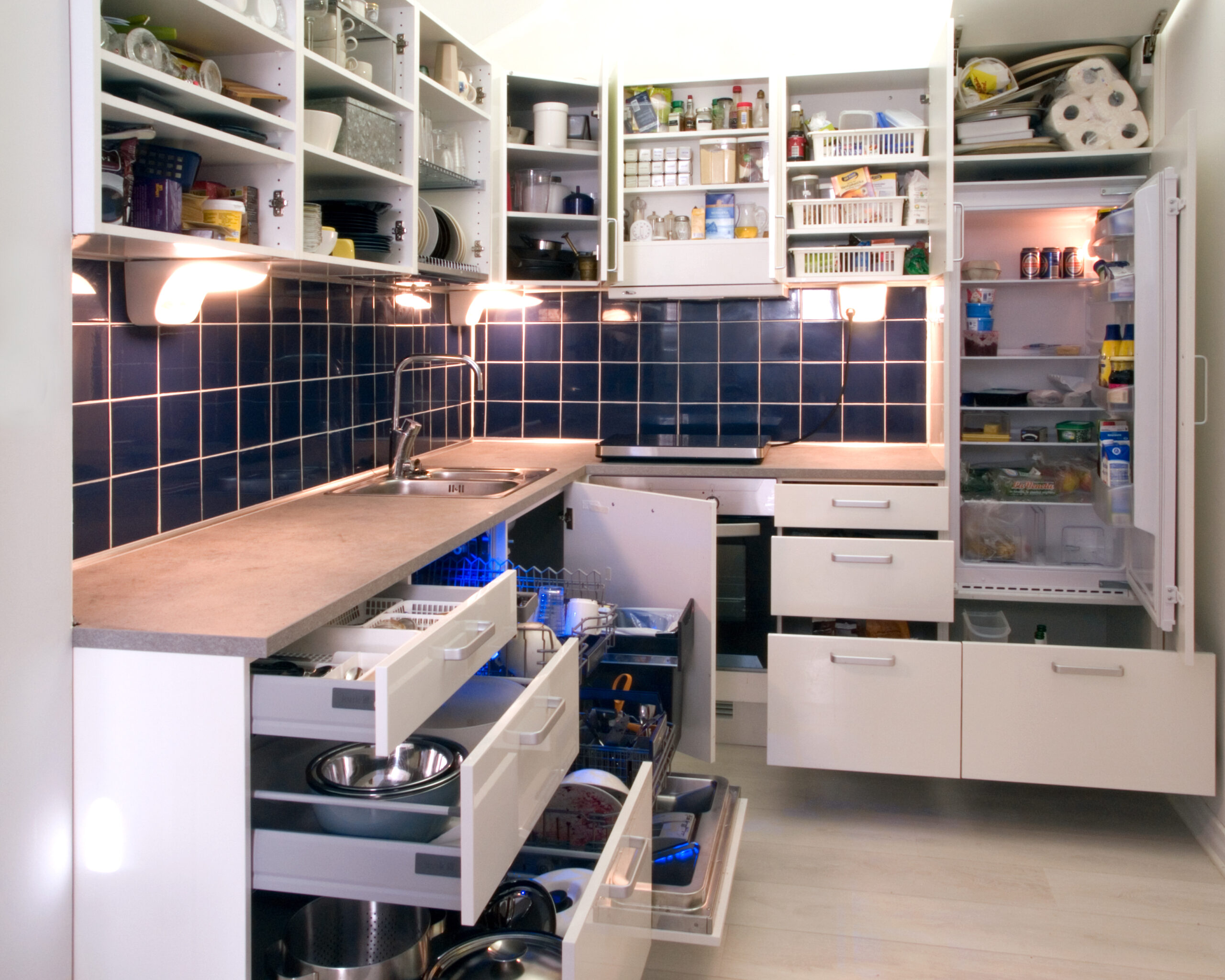 Open white kitchen cabinets showing dishes and household items inside