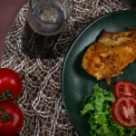 Um prato vibrante com frango grelhado, arroz, salada e tomates, perfeito para uma refeição saudável.