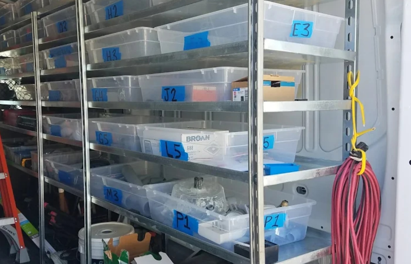 Clear storage bins with blue labels on metal shelves