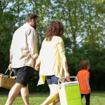 Pessoas caminhando com itens de piquenique em um parque