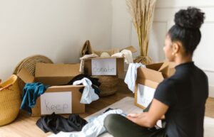 Person sorting clothes beside labeled decluttering boxes on the floor