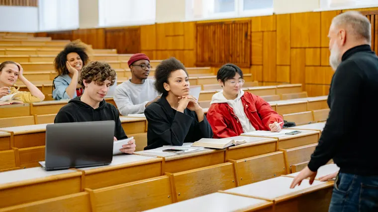 Pessoas sentadas em grupo em uma sala de aula, em um ambiente de estudo