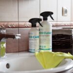 Bathroom cleaning bottles and yellow cloth beside a sink