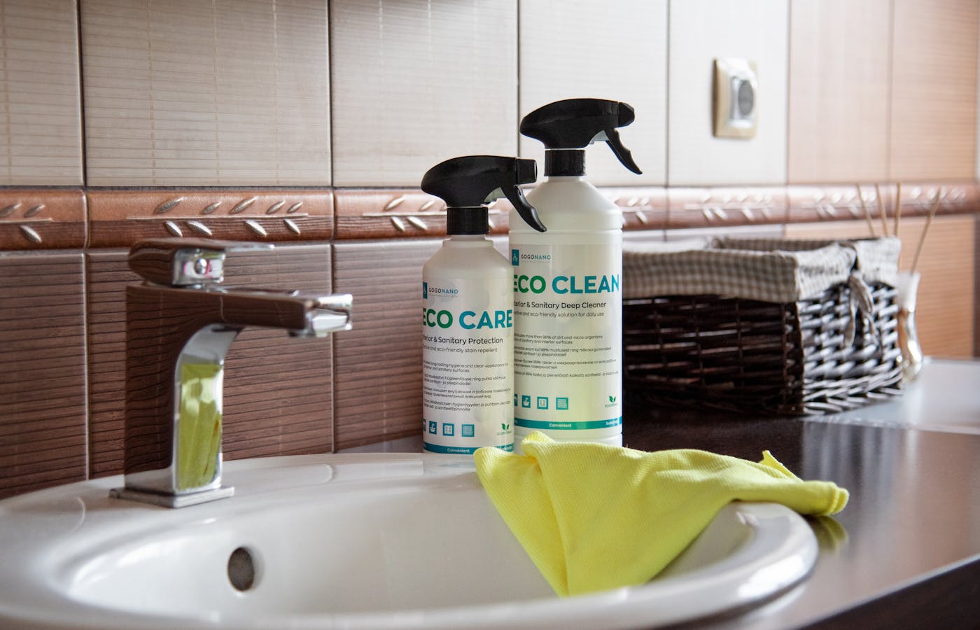 Bathroom cleaning bottles and yellow cloth beside a sink