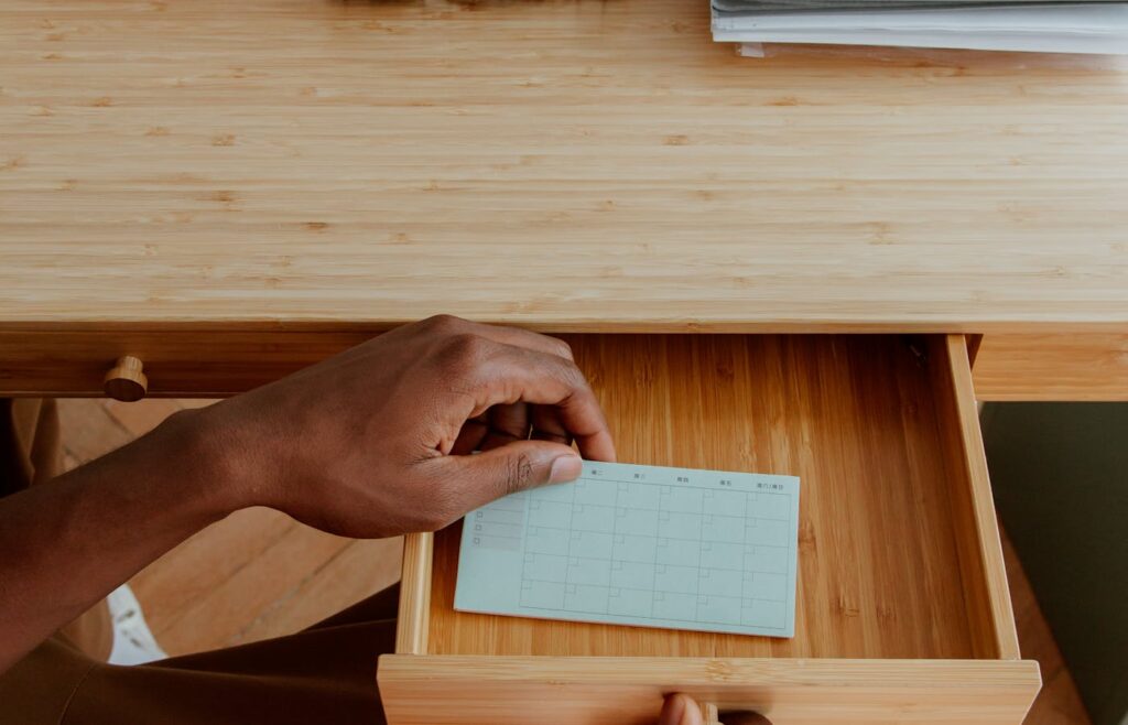 Hand placing a paper card inside a wooden drawer