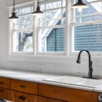 Kitchen sink with black faucet under large windows