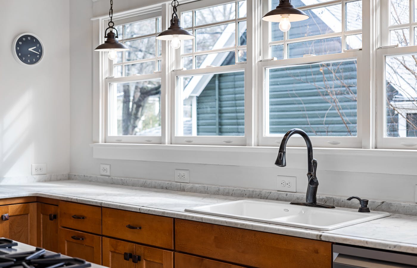 Kitchen sink with black faucet under large windows