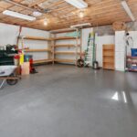 Garage with wooden shelves, a ladder, tools, and open floor space