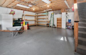 Garage with wooden shelves, a ladder, tools, and open floor space