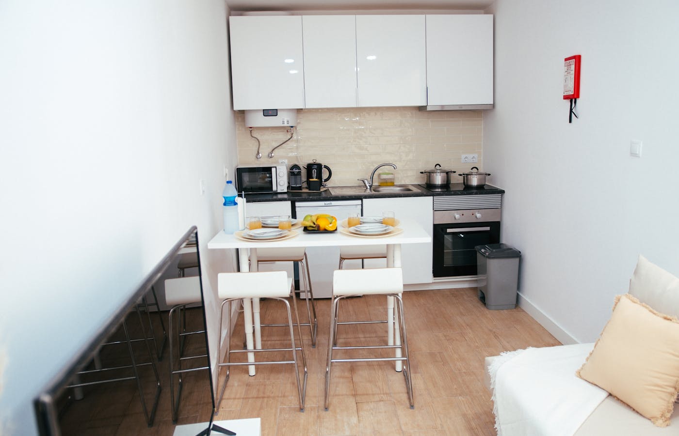 Compact apartment kitchen and dining area with white cabinets