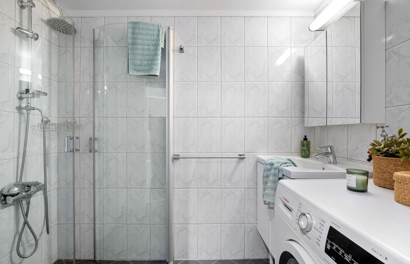 Clean tiled bathroom with glass shower and sink