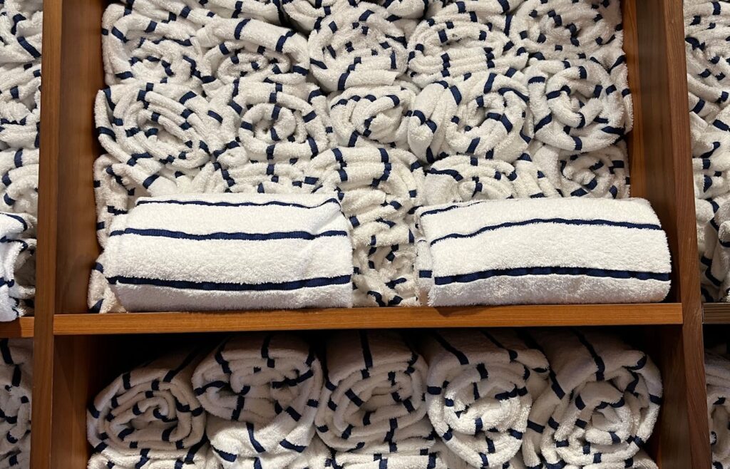 Rolled white towels arranged on wooden shelves for linen storage