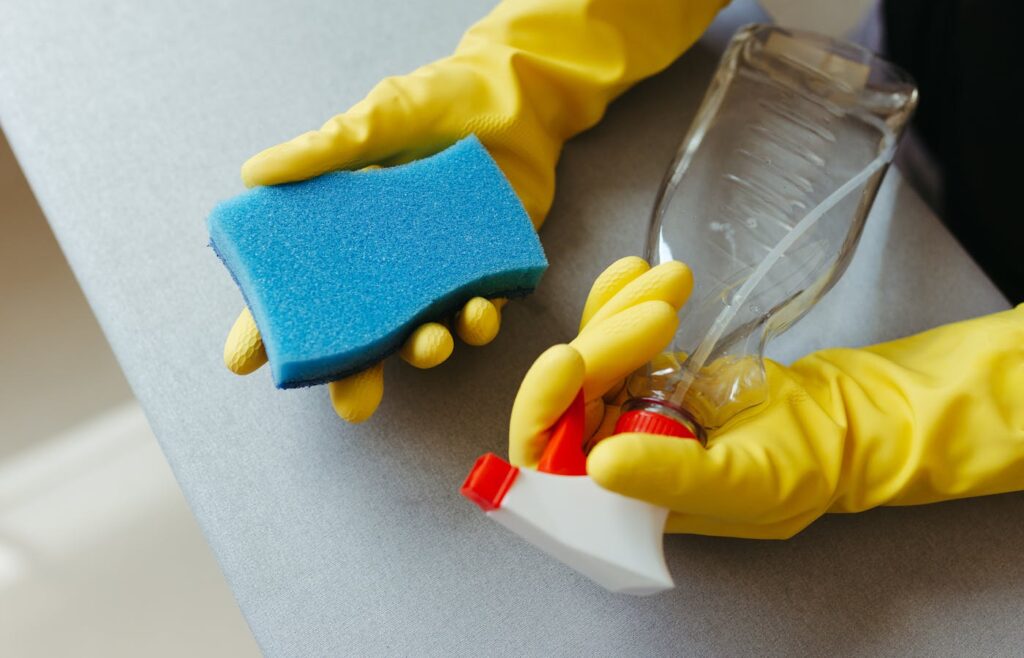 Yellow gloves sponge and spray bottle cleaning tools
