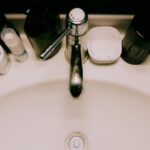 Bathroom sink with toiletries crowded around the faucet