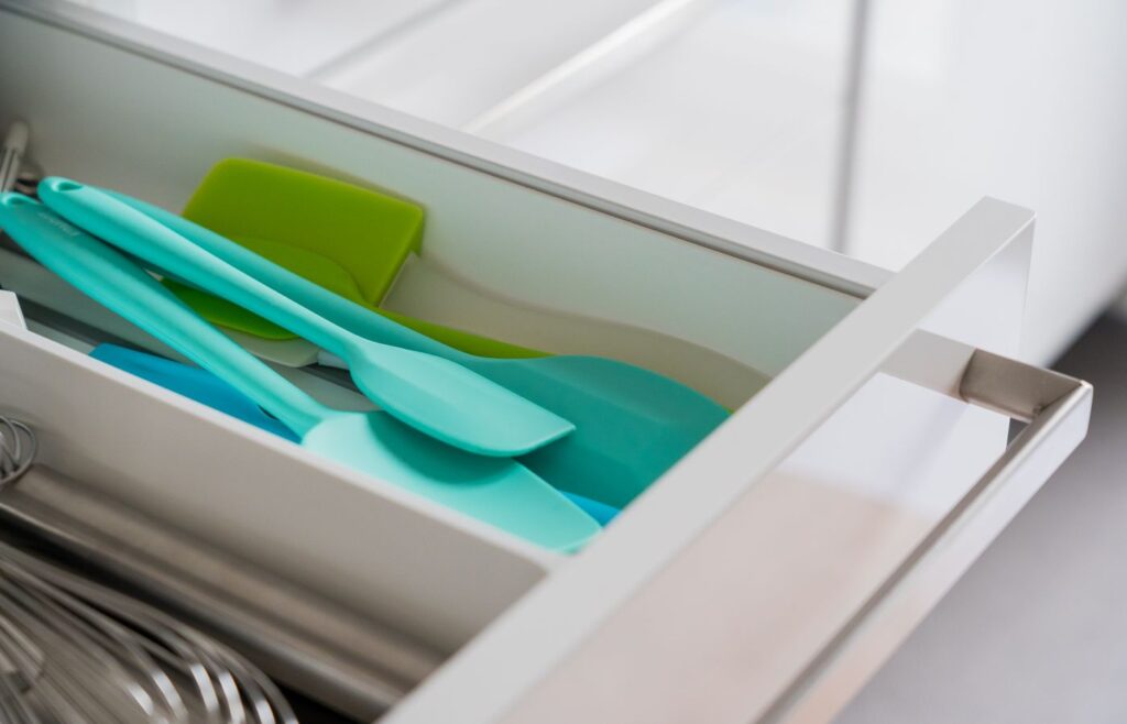 Open kitchen drawer with blue and green silicone spatulas