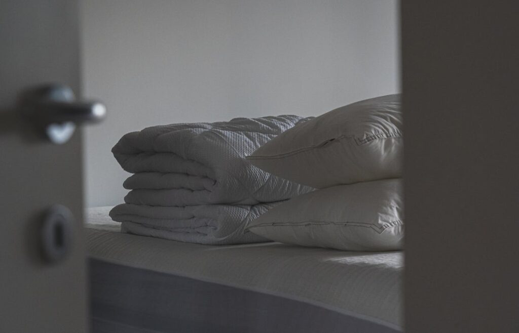 Folded white bedding and pillows on a bed