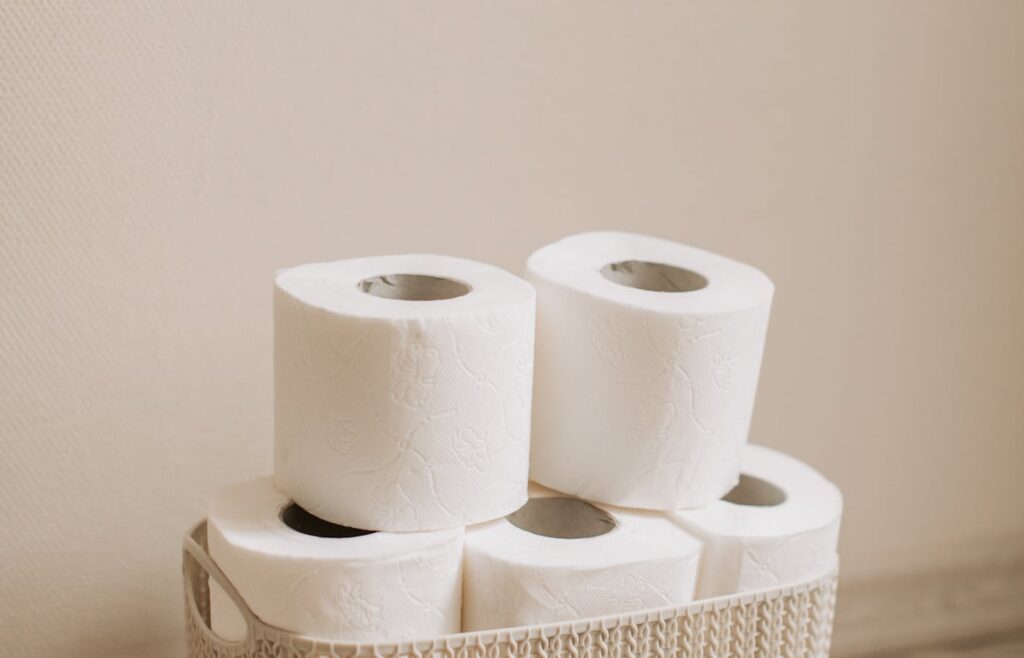 Toilet paper rolls stored inside a woven basket on a bathroom floor
