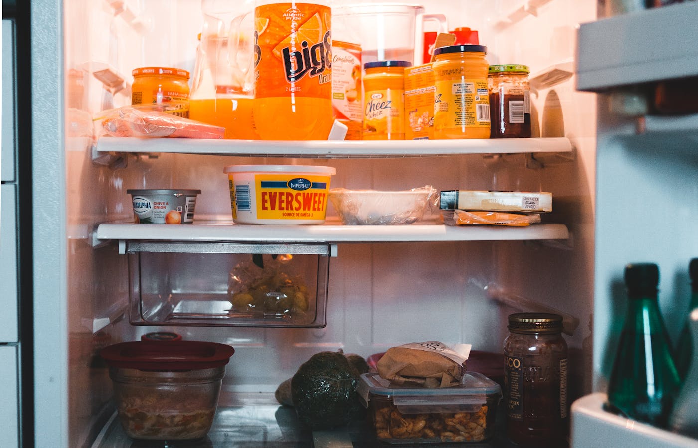 Open refrigerator with jars, containers, drinks, and food on shelves