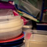 Plastic food containers and colorful lids stacked inside a cabinet