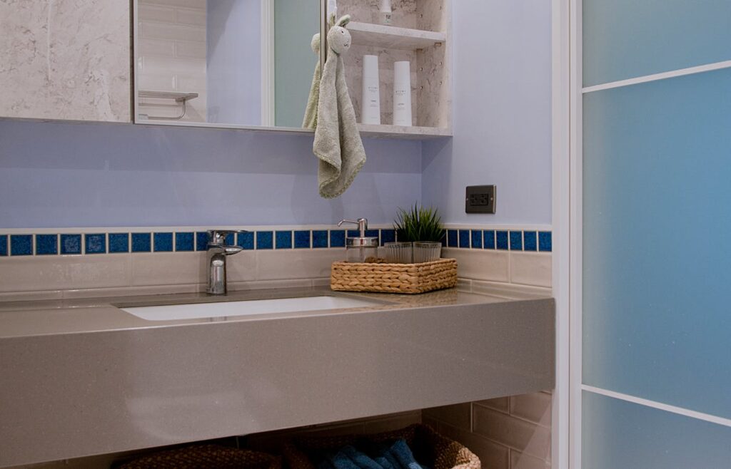 Bathroom sink with mirror cabinet shelves, toiletries, towel, and woven basket