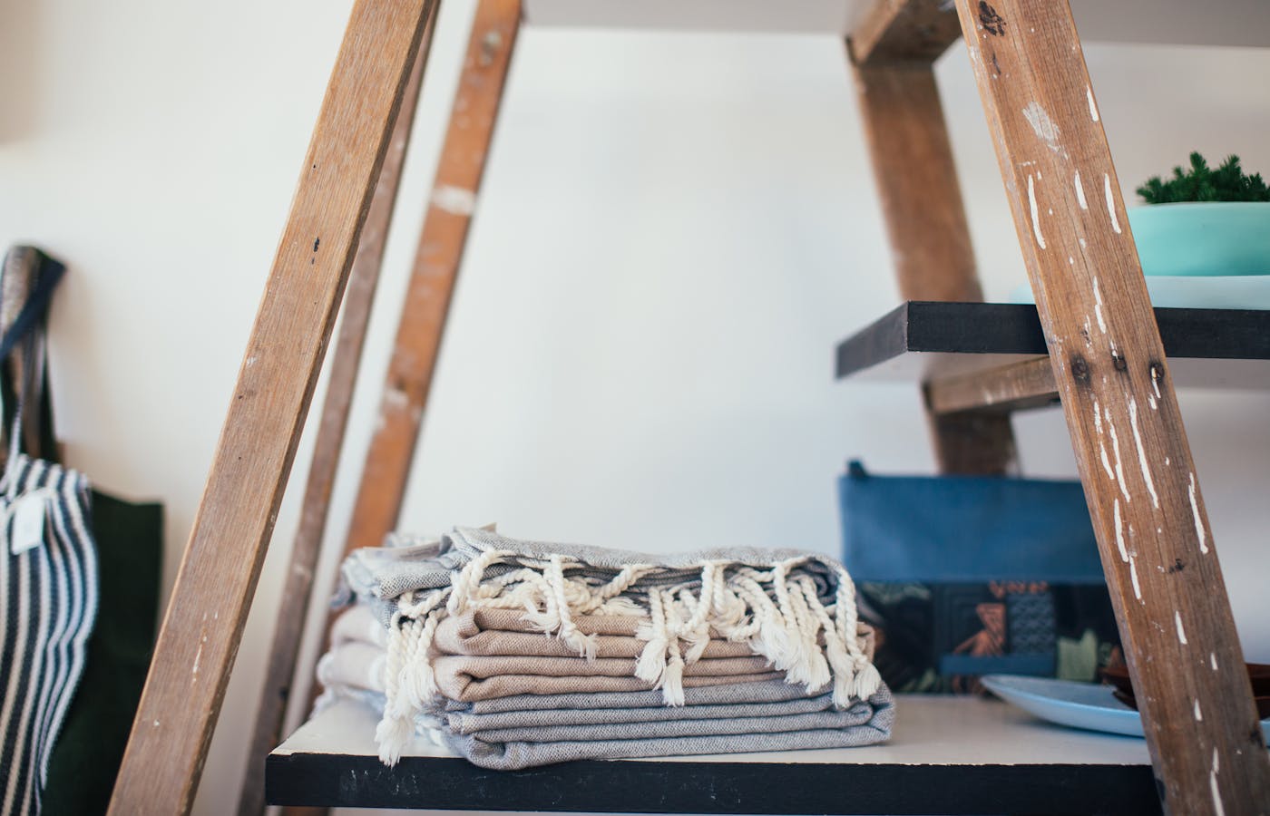 Folded clean towels stacked on a wooden shelf in a linen closet
