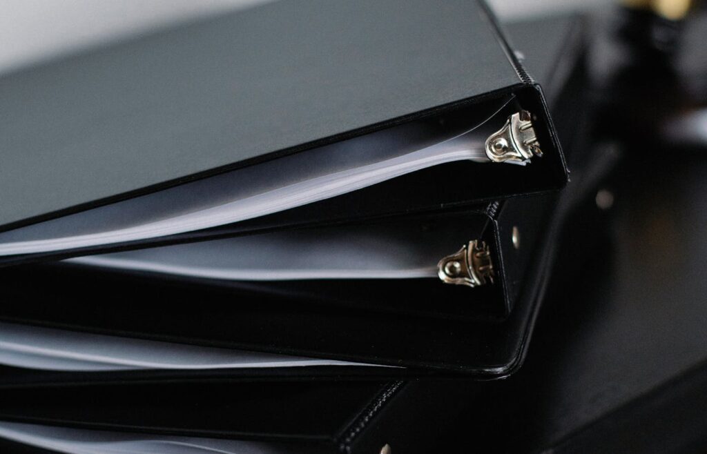 Black binders filled with organized paper documents
