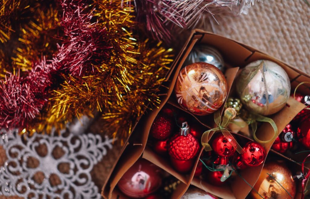Holiday decor storage box with red ornaments, gold tinsel, and garland