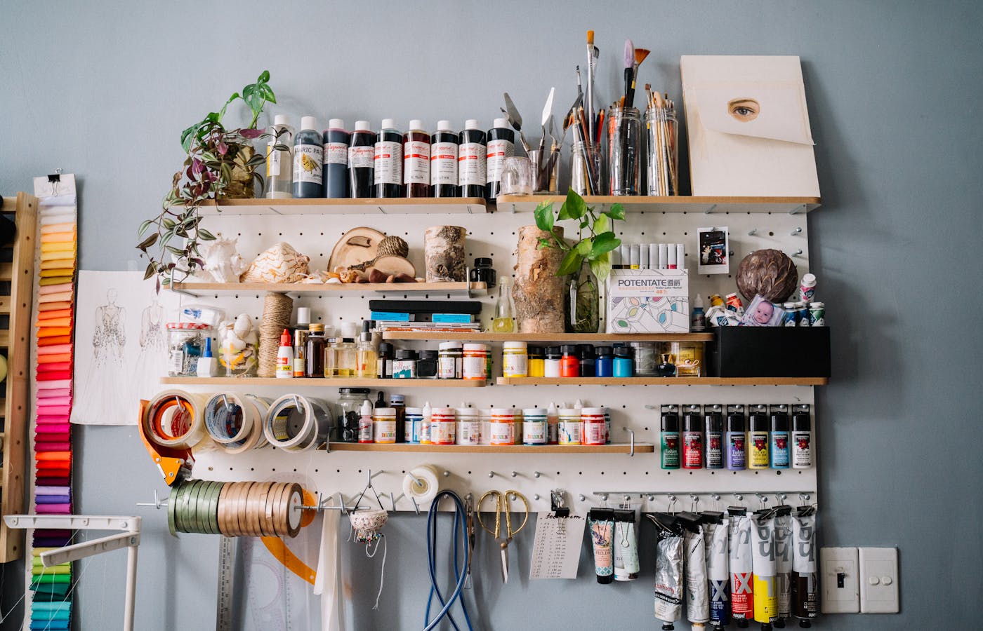 Wall shelves filled with paint bottles brushes tape and craft supplies