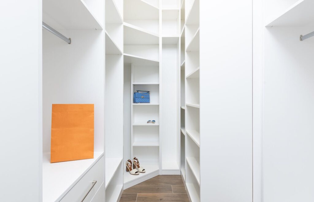 White closet shelves with shoes and a blue bag