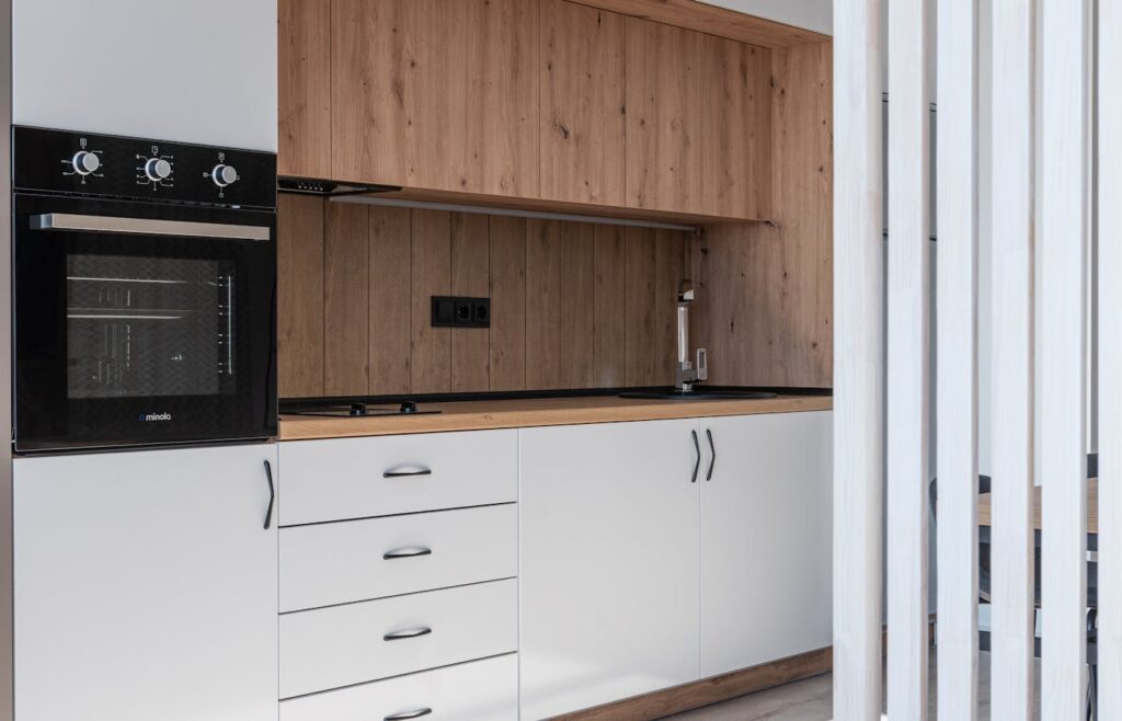 Compact apartment kitchen with wood cabinets and white room divider