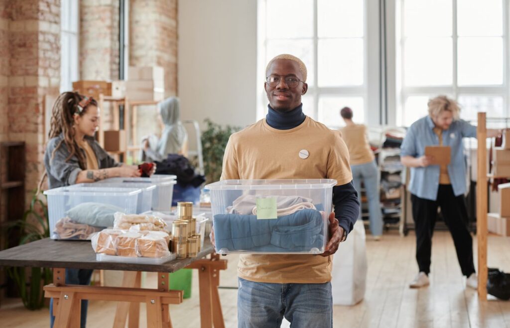 Person holding a clear decluttering bin filled with folded clothes
