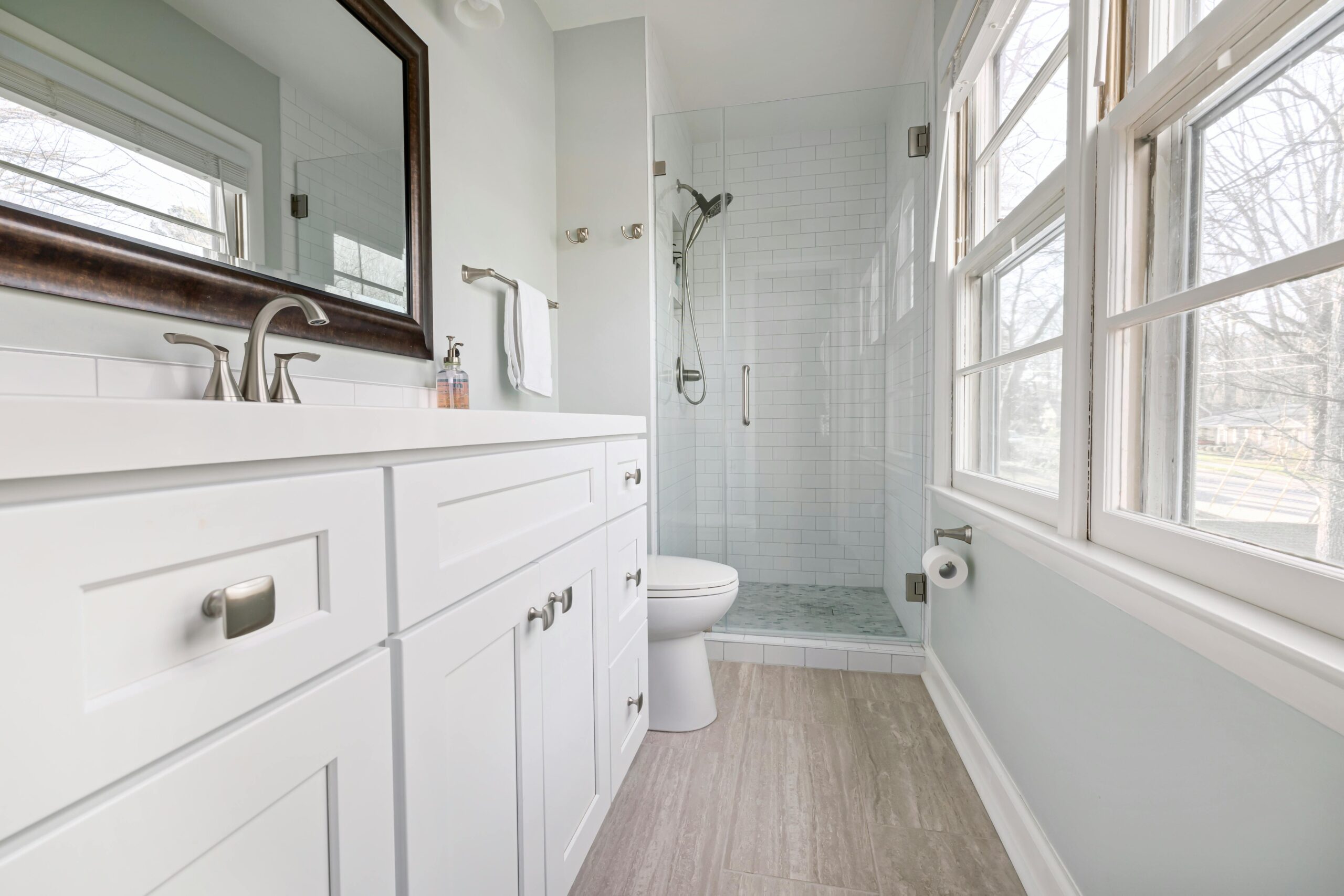 White bathroom with a clear glass shower door and vanity