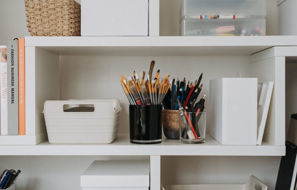 White shelf with paint brushes pencils storage boxes and craft supplies
