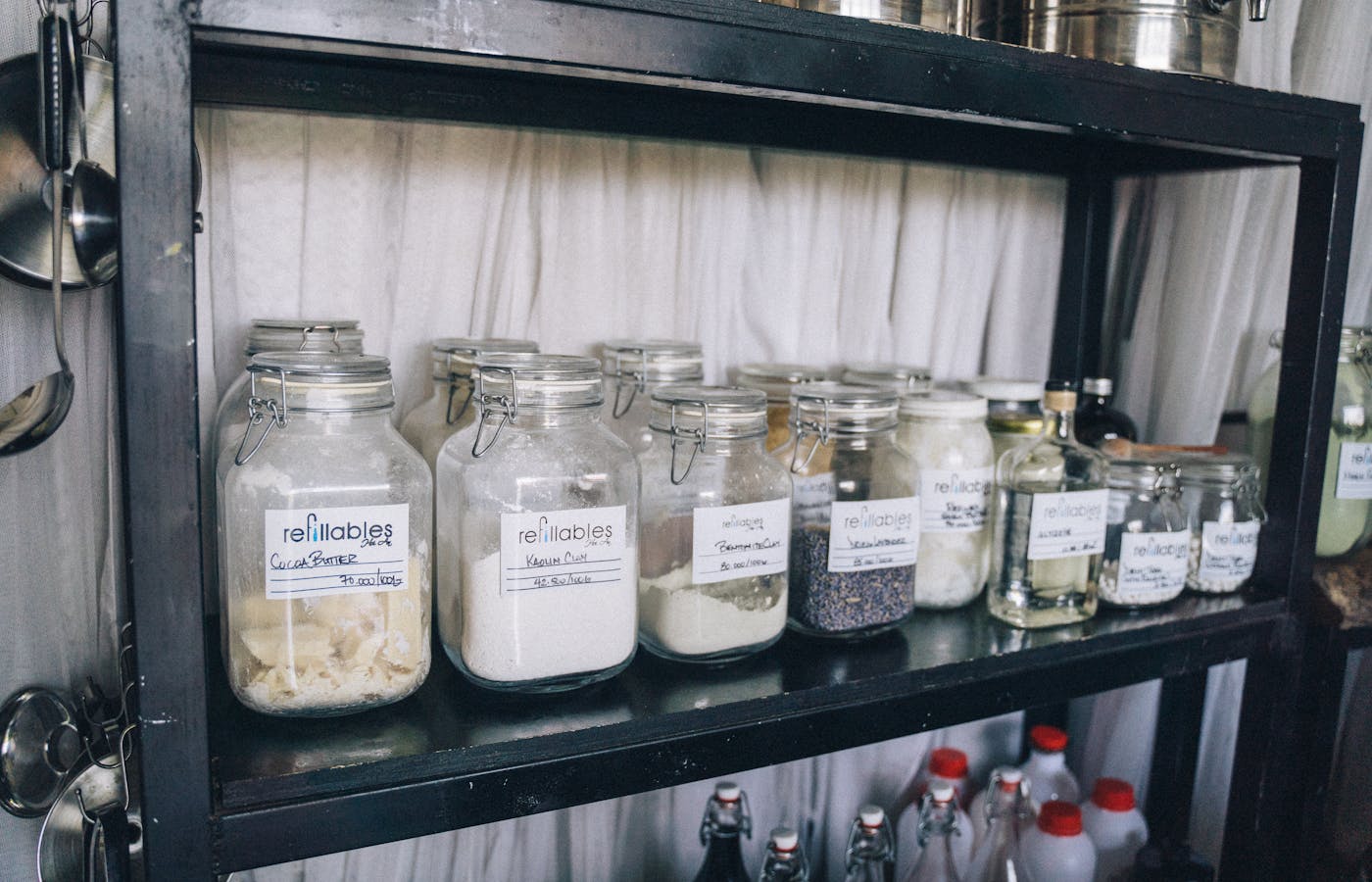 Labeled glass jars lined up on a black pantry shelf
