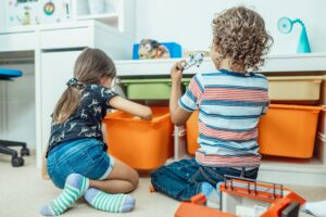 Children playing beside orange toy storage bins