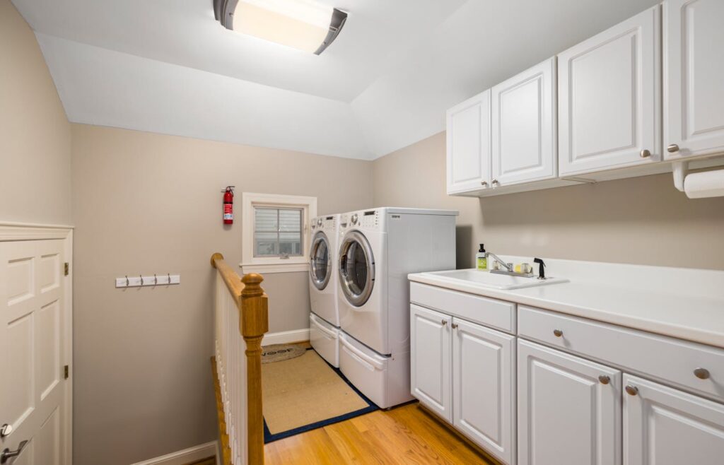 Laundry room with white cabinets above washer and dryer