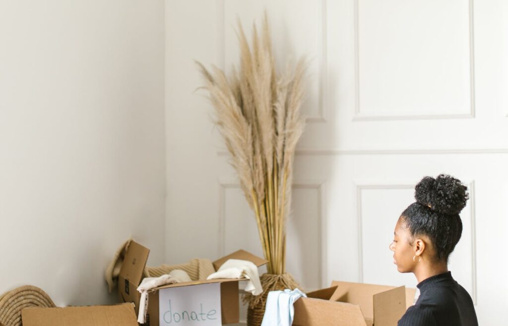 Person sitting beside clothing donation boxes during decluttering