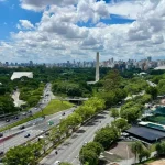 Vista aérea do Parque Ibirapuera, em São Paulo, mostrando vegetação, estradas e o horizonte da cidade.