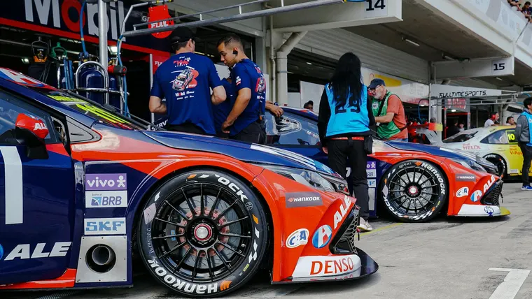 carros de corrida nos boxes sendo vistoriados por equipe